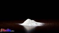 White powderlokking like cocain on dark brown empty Kitchen table